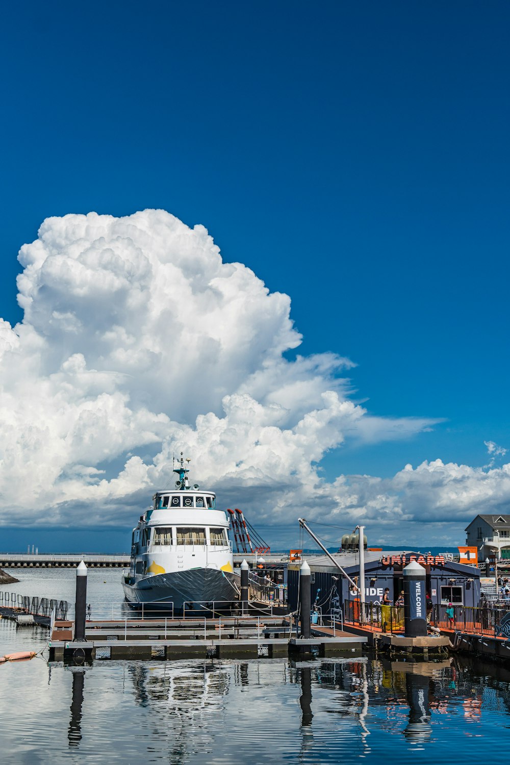 nave bianca e blu sul molo sotto il cielo nuvoloso blu e bianco durante il giorno