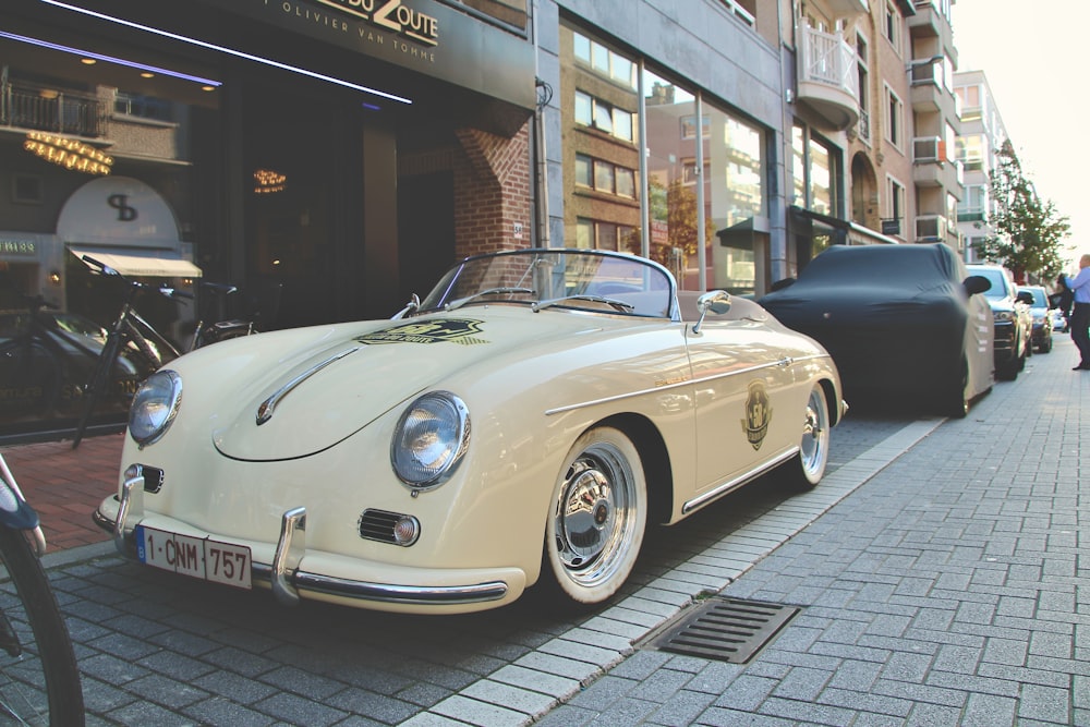 white porsche 911 parked near brown building