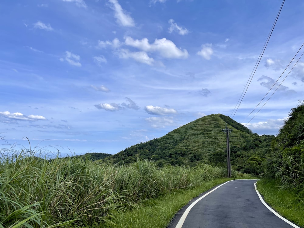 strada di cemento grigio fra il campo di erba verde sotto il cielo blu e le nuvole bianche durante il giorno