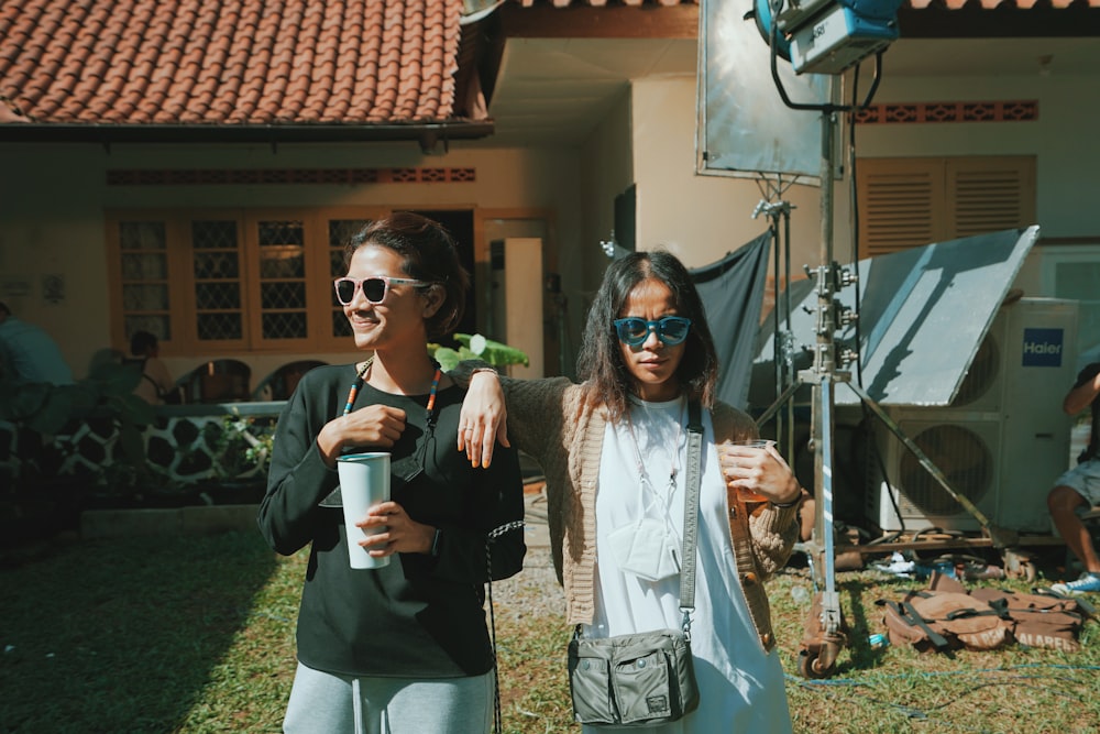 woman in black sunglasses holding white cup