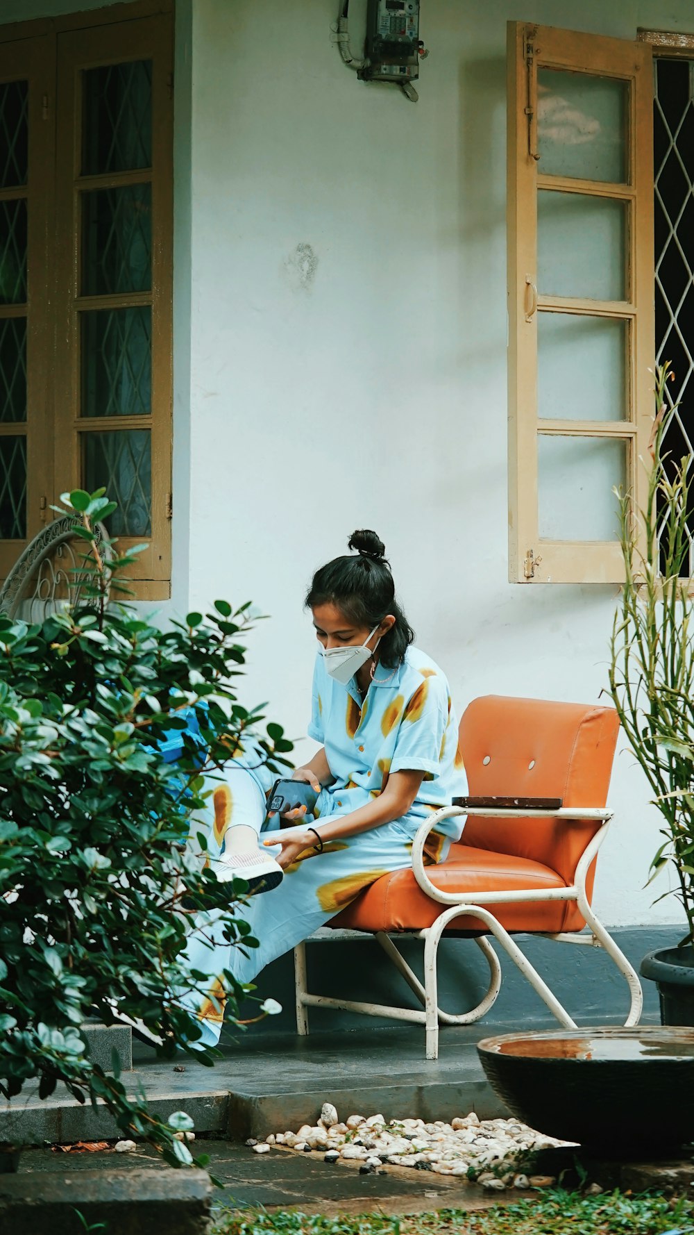 Femme en chemise à manches longues bleue et blanche assise sur un fauteuil marron