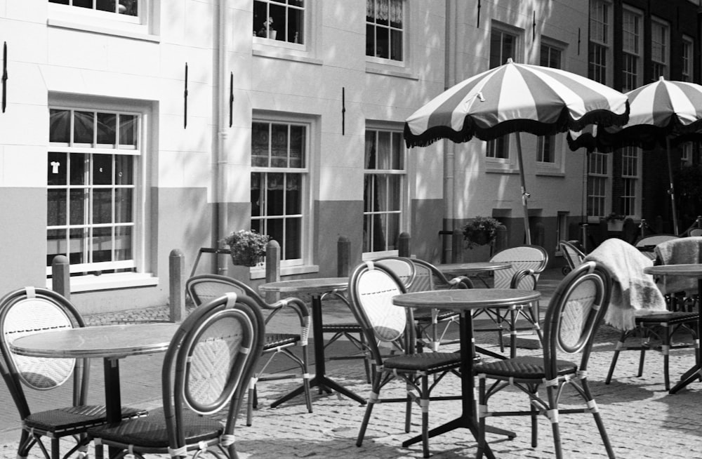 grayscale photo of bicycle parked beside table and chairs