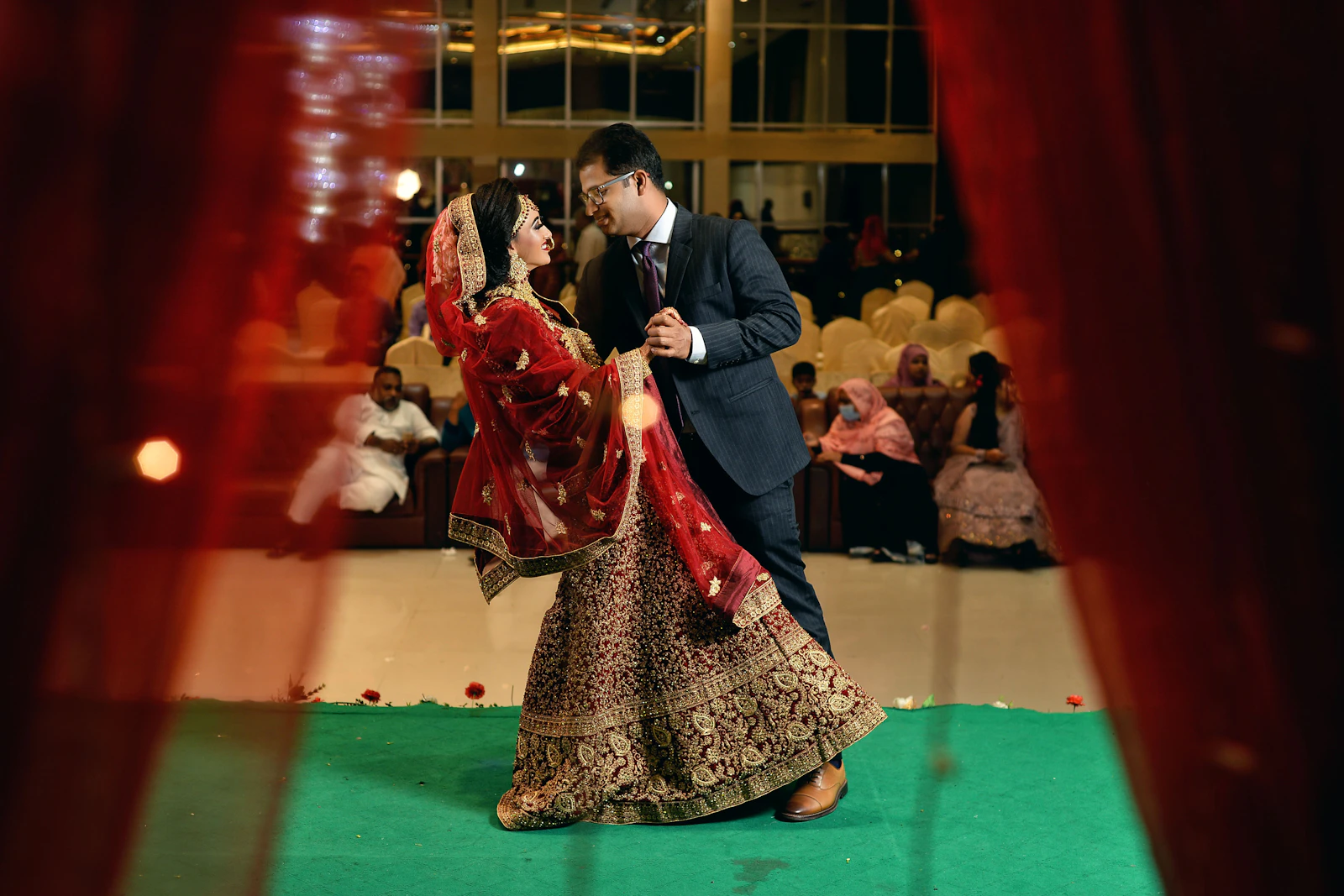 A woman in a red and black outfit dancing at a sangeet