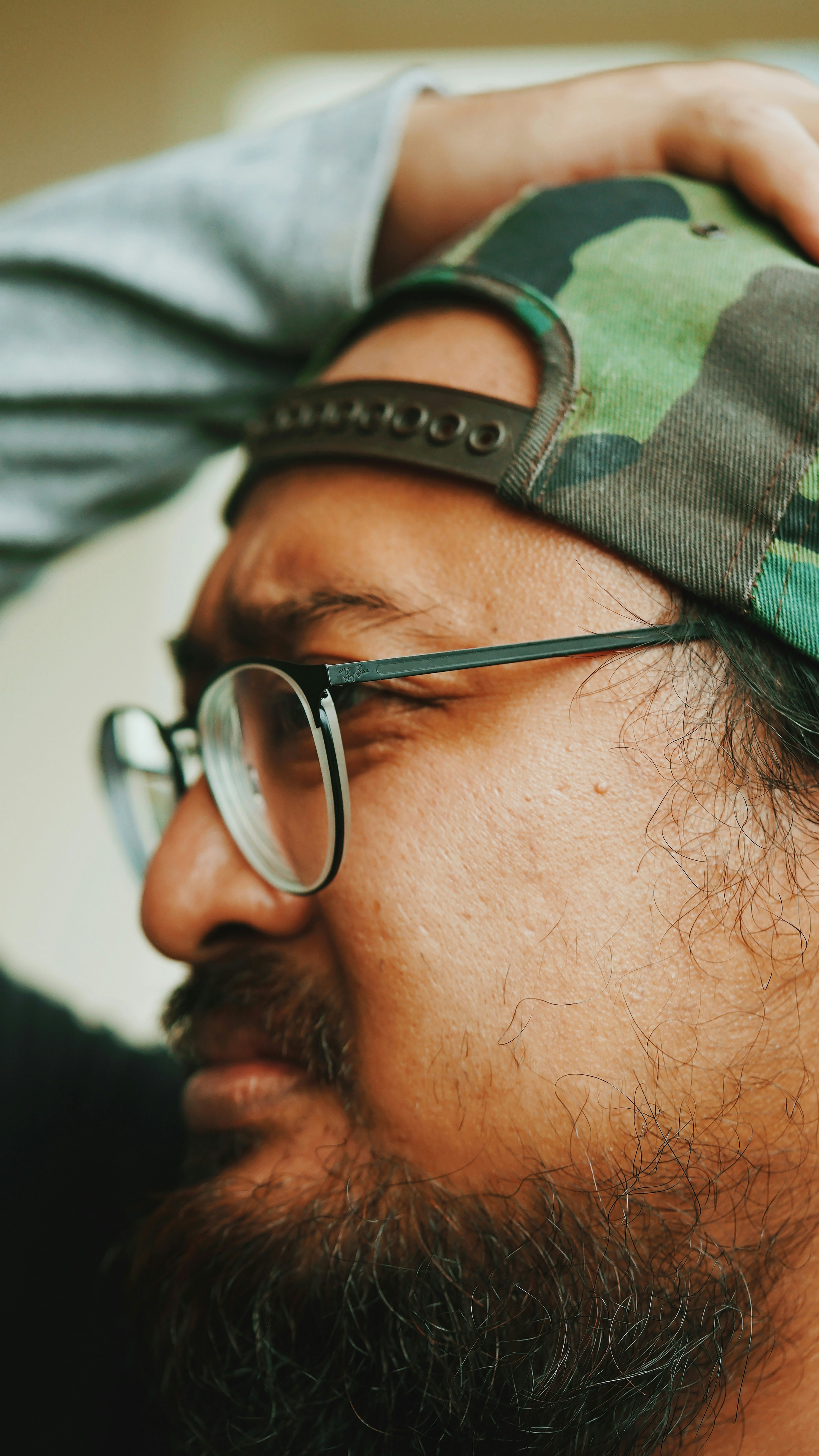 man in green and black camouflage hat and black framed eyeglasses