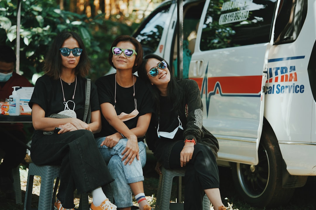 3 women sitting on white car