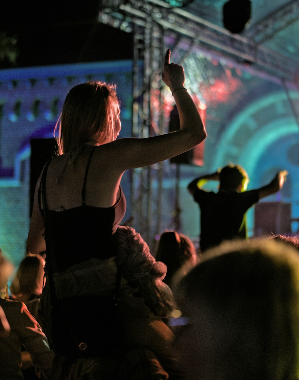 woman in black spaghetti strap top raising her hands