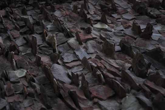 A jagged, uneven surface composed of variously sized and shaped slate or stone pieces, arranged with sharp, pointed ends protruding upward. The stones have an irregular, rough texture, and the surface appears to have a natural, rugged pattern.