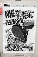 A poster with bold text in Polish related to political or military issues, featuring a black and white illustration of a large animal, possibly a bull, with human figures and a vehicle or military aircraft. The figures are depicted with expressive gestures, suggesting a theme of protest or opposition.