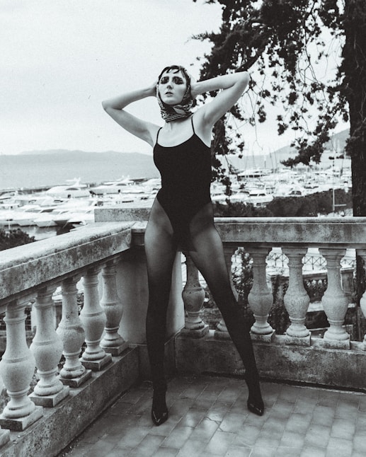 woman in black one piece swimsuit standing on concrete fence