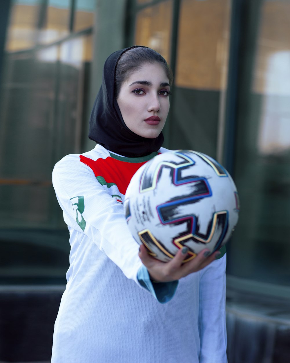 woman in white and blue long sleeve shirt holding white and black nike soccer ball