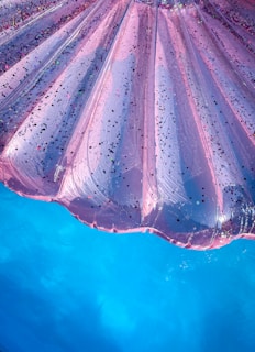 A close-up view of a pink inflatable pool float with sparkles, set against the vibrant blue water of a pool.