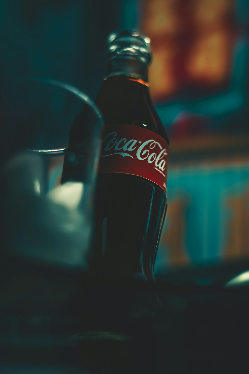 Bottiglia di Coca Cola accanto a un bicchiere trasparente