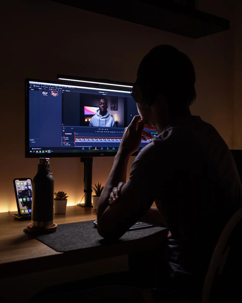 Iemand bewerkt beeld op een scherm in een donkere werkruimte