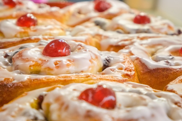 Baker carefully glazing freshly baked sweet rolls in the kitchen.