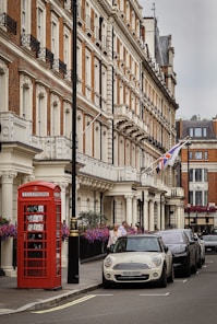 red telephone booth near black car and building during daytime