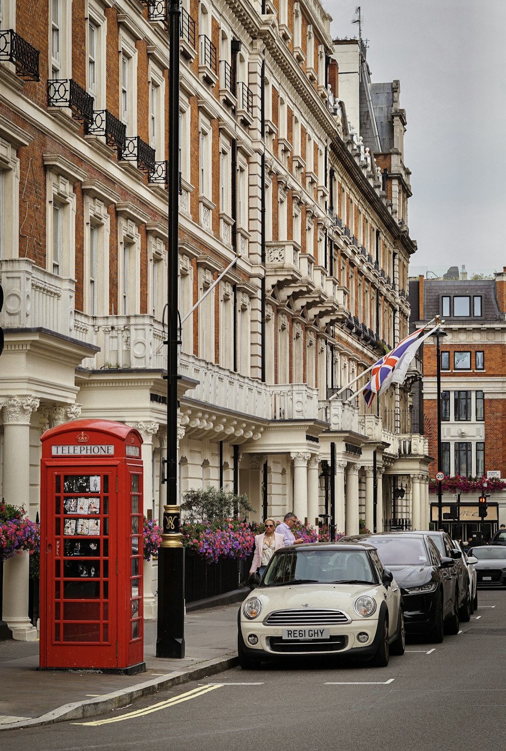 red telephone booth near black car and building during daytime