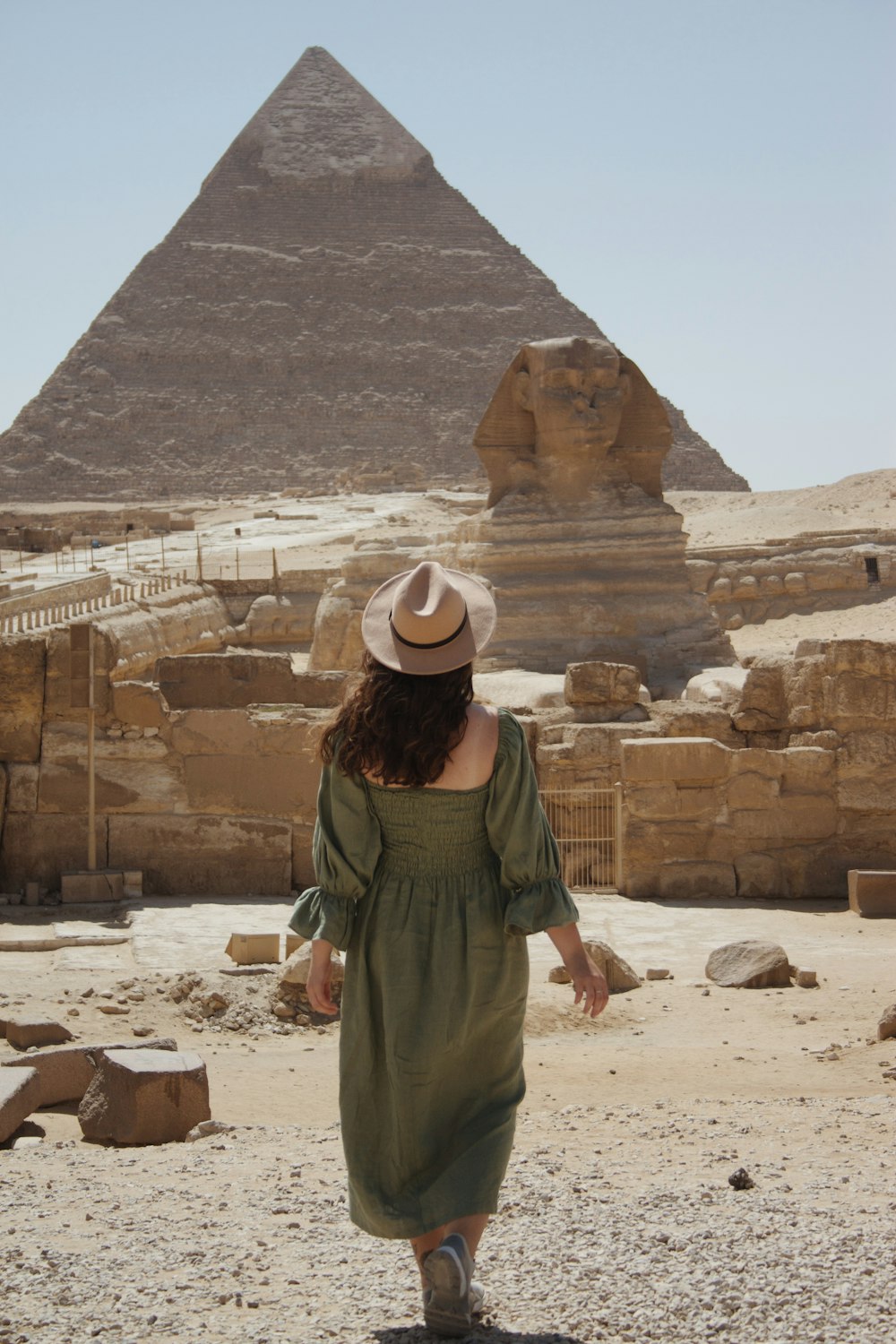 woman in green and brown dress standing on brown sand during daytime