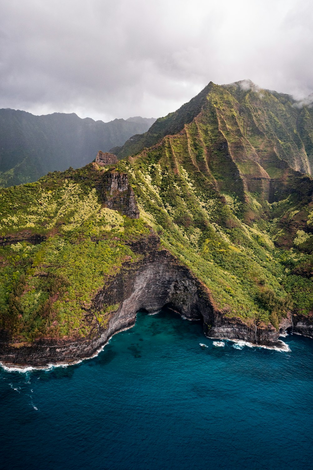 green and brown mountain beside blue sea during daytime