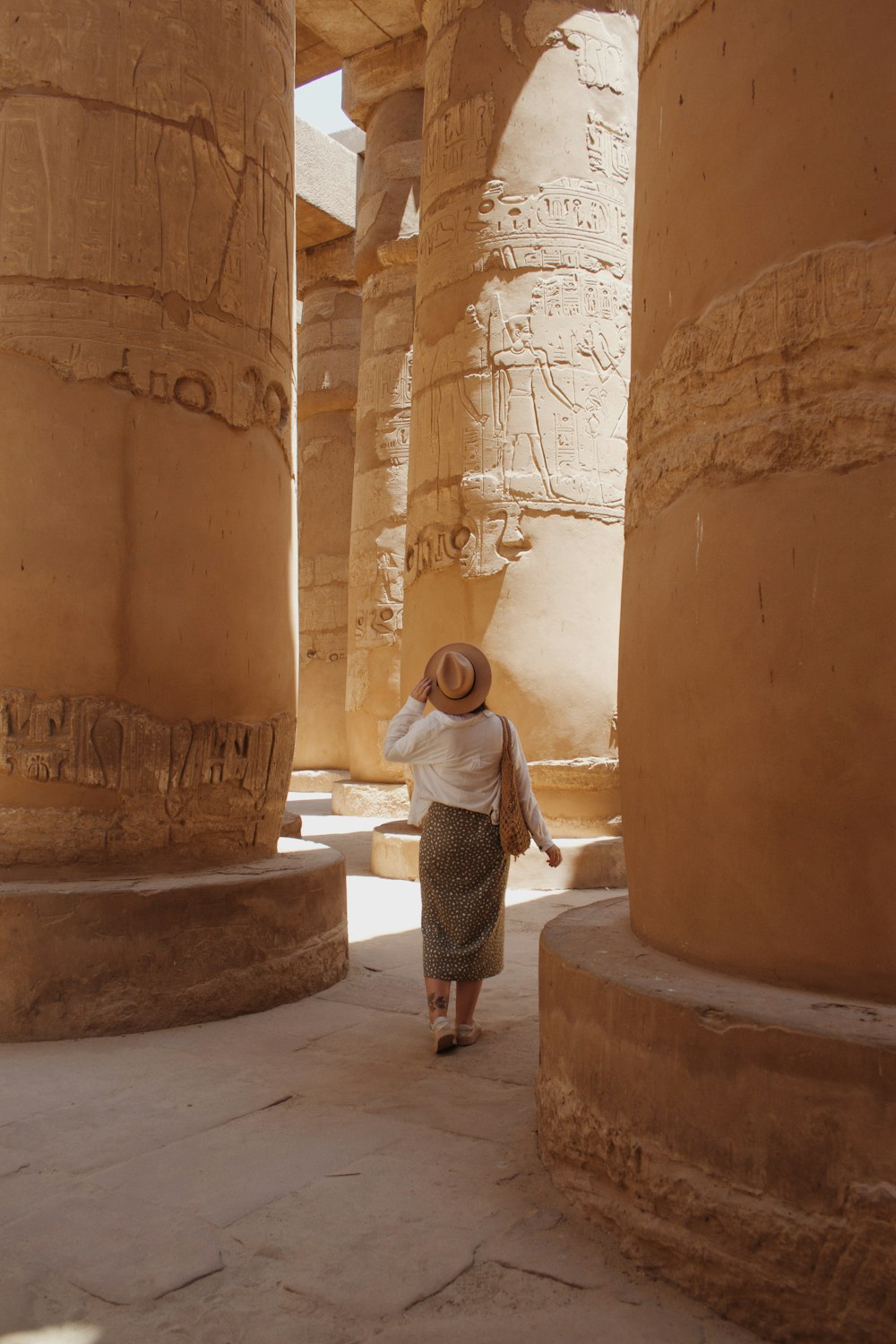 woman in white long sleeve shirt and black skirt standing in front of brown concrete wall