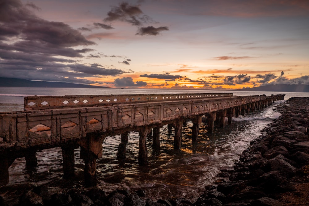 brown wooden dock on sea during sunset