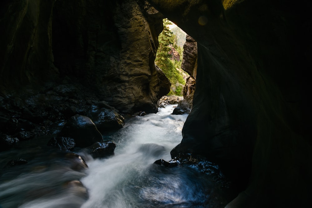 water falls between brown rock formation during daytime