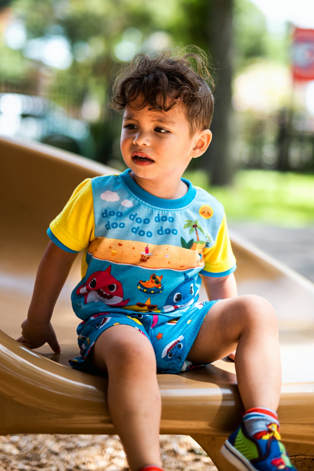 boy in yellow blue and red crew neck t-shirt sitting on brown wooden bench during