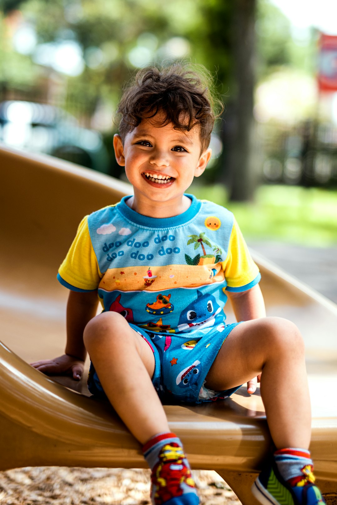 boy in yellow and blue crew neck t-shirt sitting on brown wooden bench during daytime