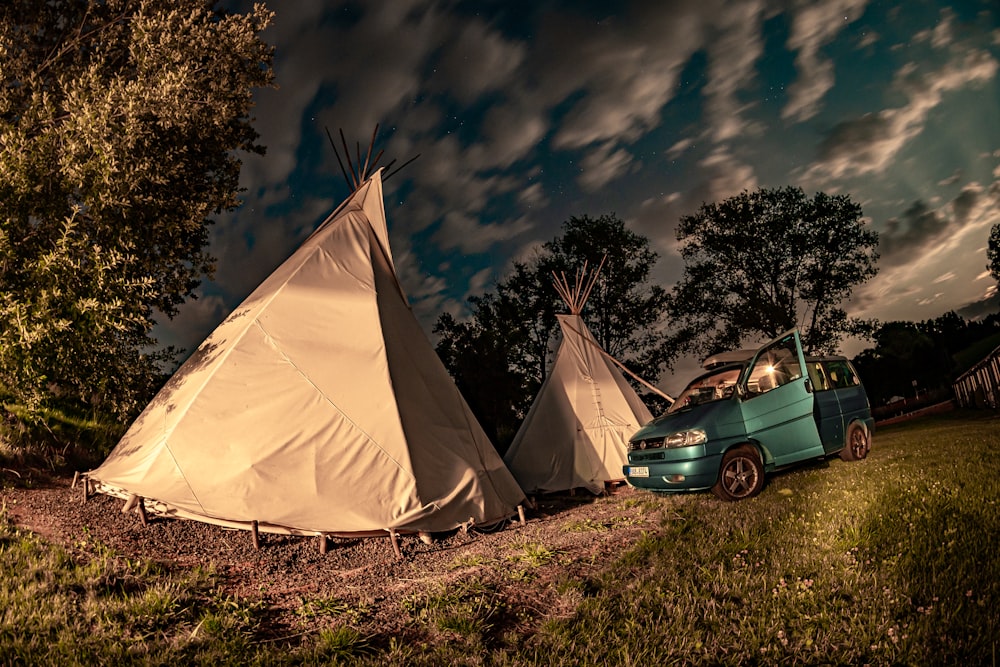 blue car parked beside white tent during night time