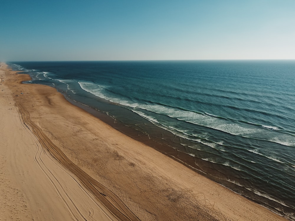 brown sand near body of water during daytime