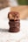 A stack of three chocolate-covered treats, with the one on top partially bitten to reveal a caramel-like filling and crispy interior. The treats are placed on a light surface with chocolate shavings scattered around.