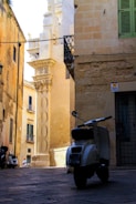 black motorcycle parked beside brown concrete building during daytime