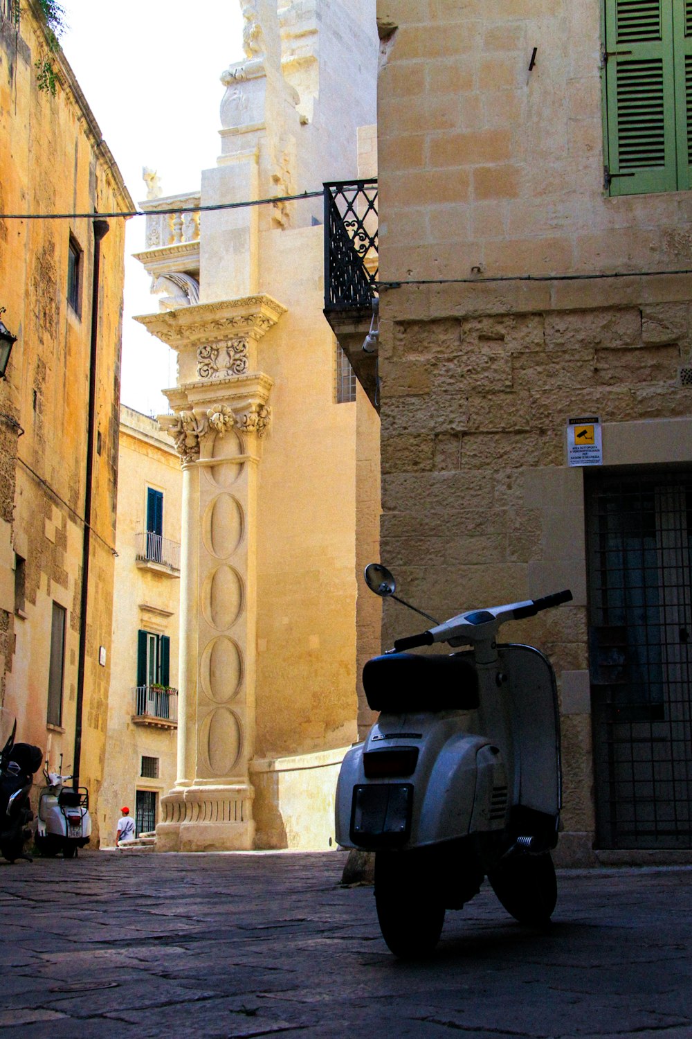 black motorcycle parked beside brown concrete building during daytime