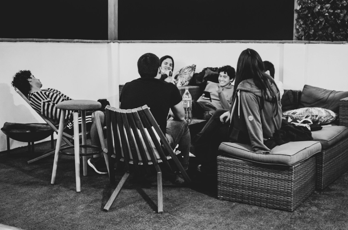 Group of friends sitting on a bench, watching a football game on TV, perfect for a game day party atmosphere.