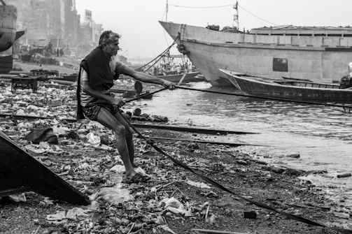 Volunteers cleaning a polluted riverbank surrounded by city buildings.