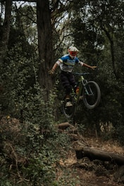 man in blue shirt riding bicycle in forest during daytime