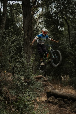 man in blue shirt riding bicycle in forest during daytime