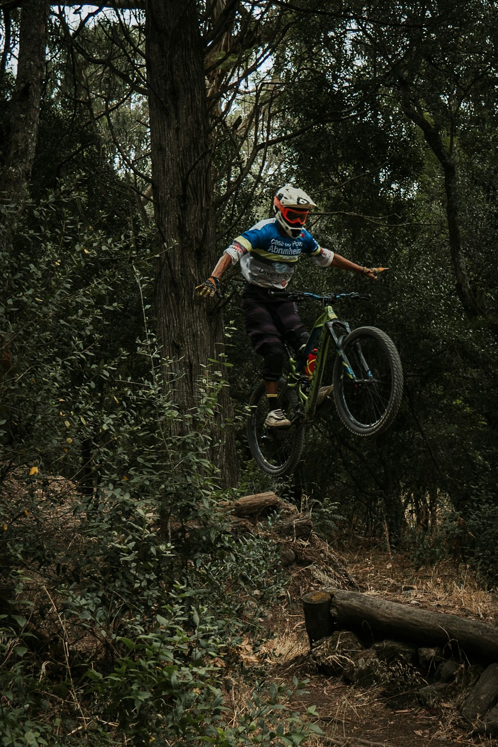 man in blue shirt riding bicycle in forest during daytime