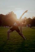 A serene yoga session taking place at sunrise in a lush green field.