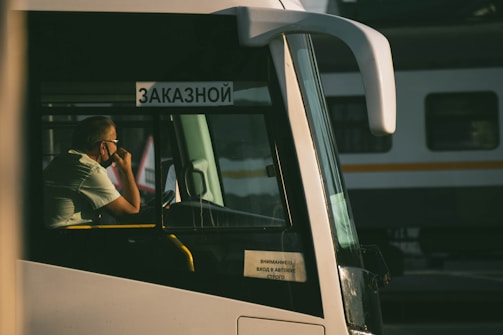 man in black t-shirt sitting on white bus