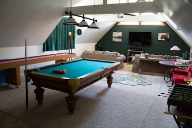 brown wooden billiard table on gray carpet