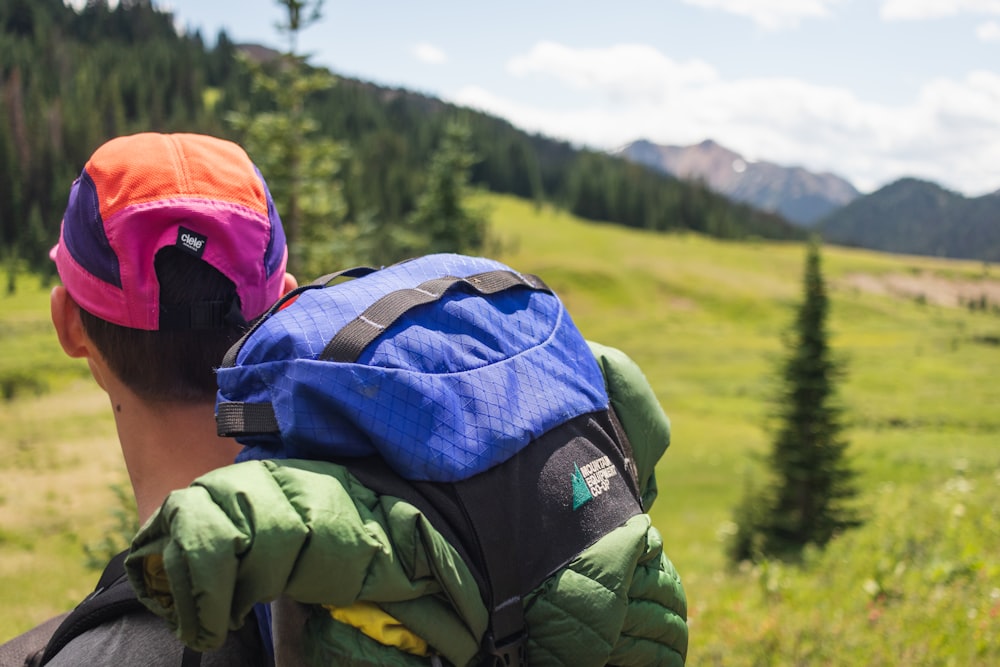 person in green jacket wearing blue and orange backpack