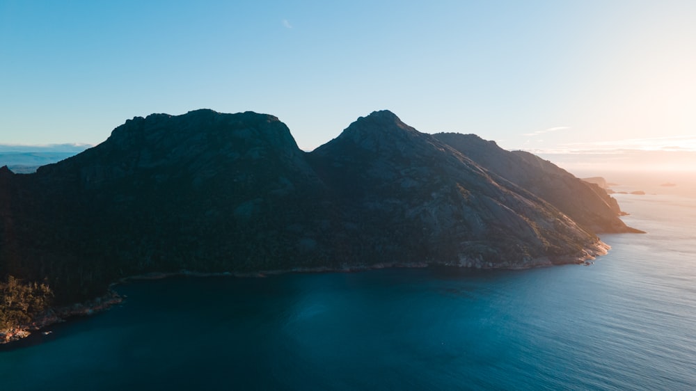 body of water near mountain during daytime