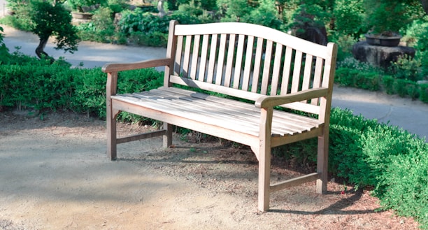 A beautifully crafted wooden garden bench surrounded by lush greenery.