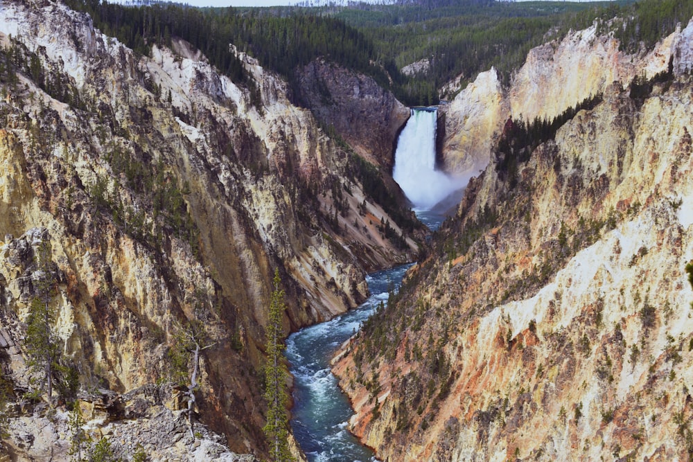 river between green and brown rocky mountains during daytime