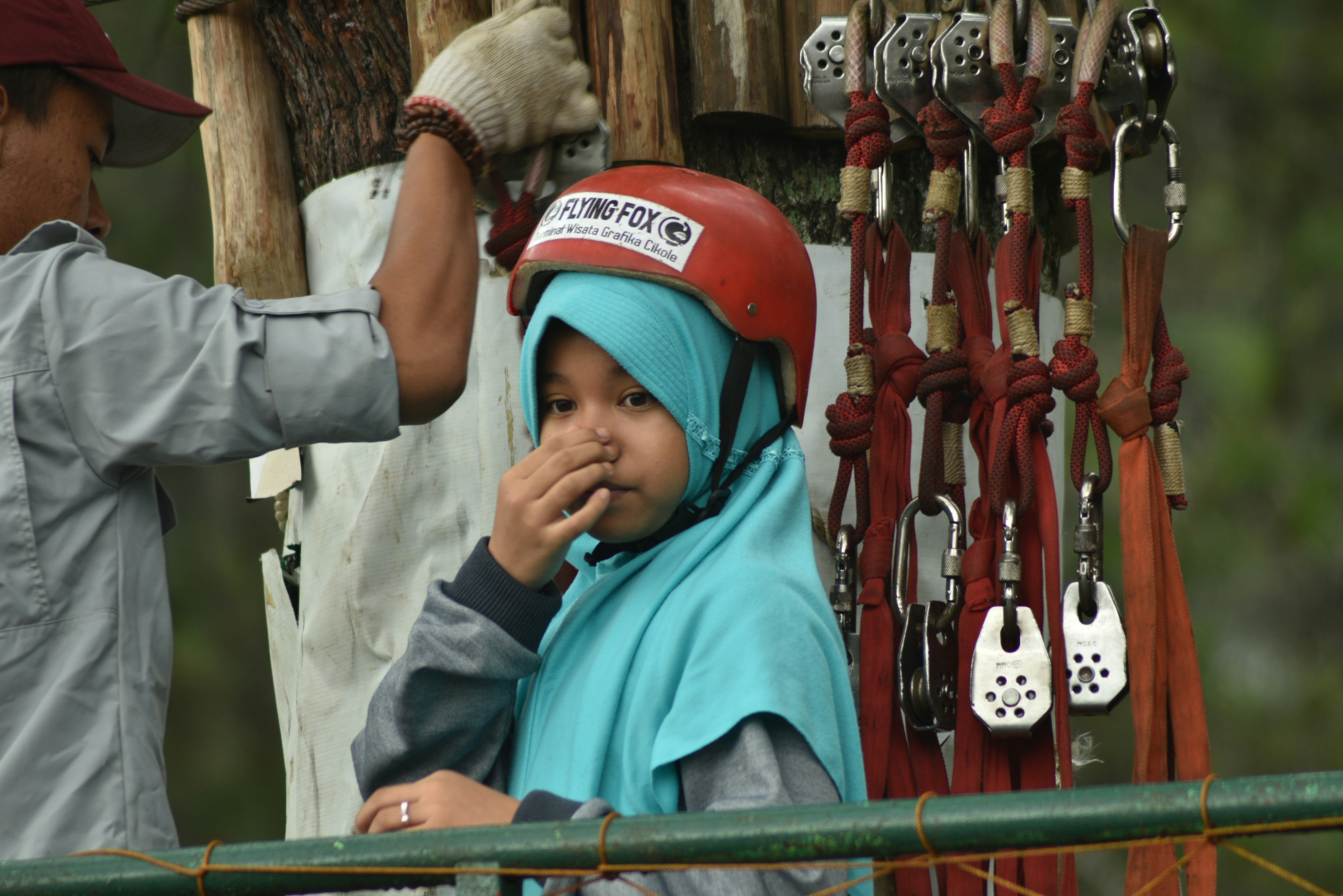 Wanita berjilbab biru duduk di bangku logam merah