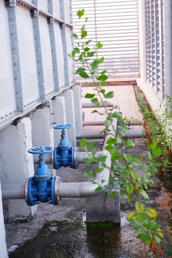 Pumps, steel pipes, and motor control valves inside a Malaysian water treatment pumping station, inspected by an engineer