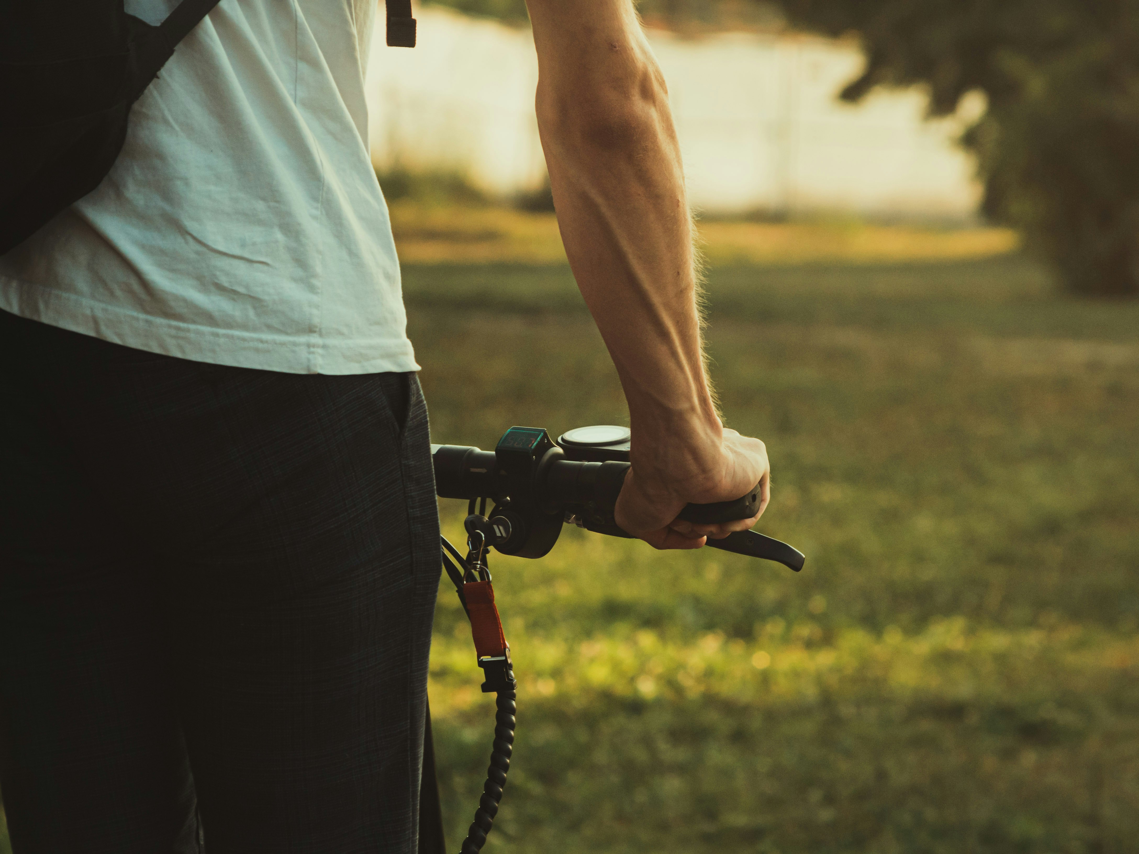 person in white shirt and black pants holding black bicycle