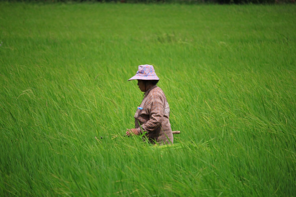 woman in brown dress wearing yellow sun hat standing on green grass field during daytime