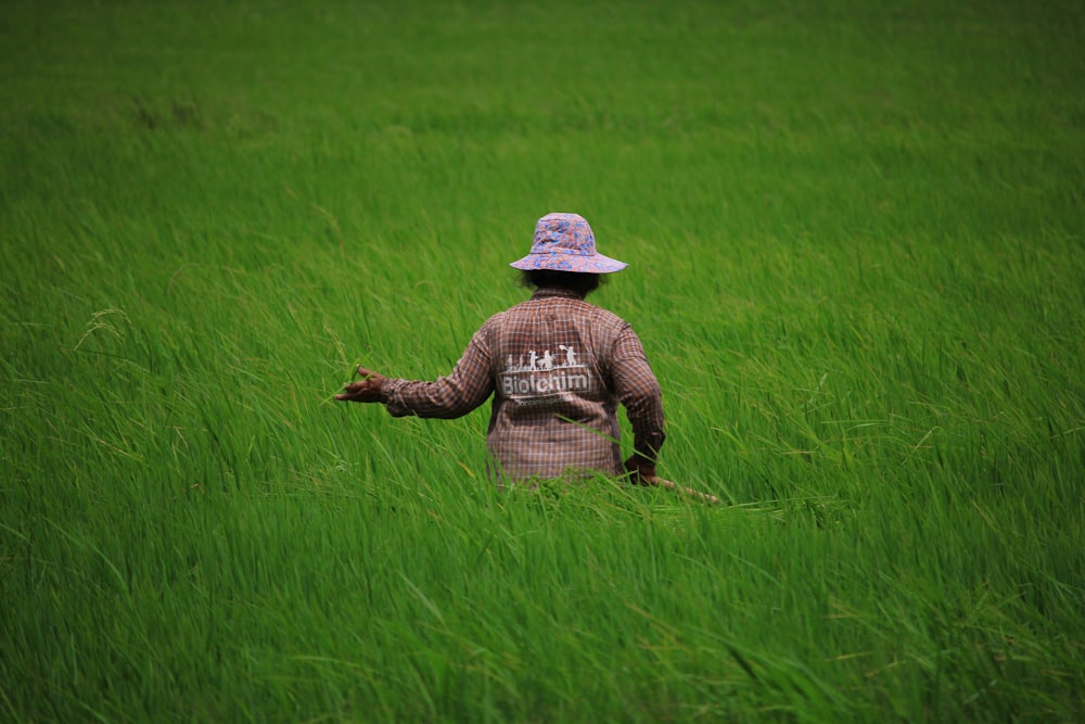 girl in brown jacket and white hat standing on green grass field during daytime