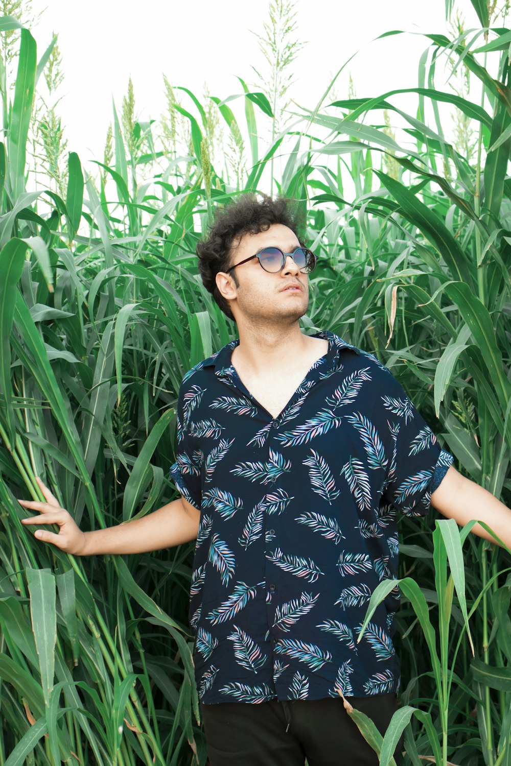 woman in black and white floral shirt standing near green plants during daytime